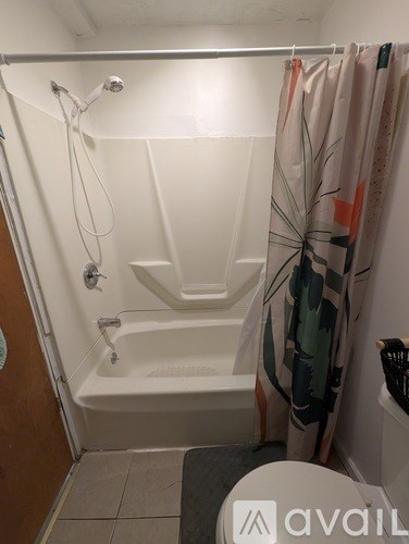 A small bathroom with a white tub and a shower curtain.