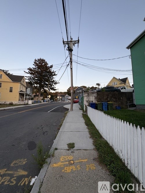 A street with a sidewalk and a white fence.