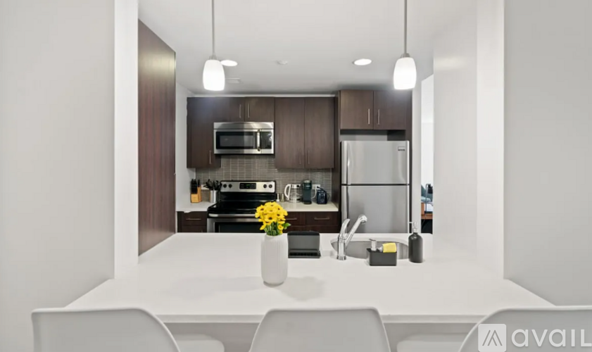 A modern kitchen with a white table and chairs, a sink, a refrigerator, a microwave, and a stove.
