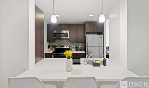 A modern kitchen with a white table and chairs, a sink, a refrigerator, a microwave, and a stove.