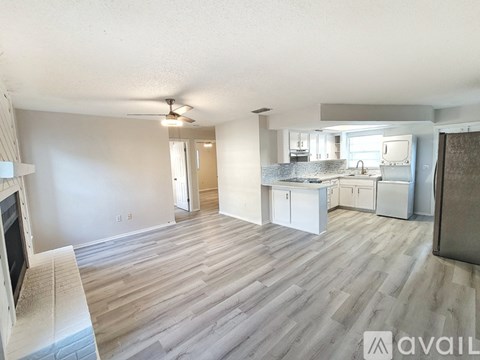 A living room with a television and a kitchen area in the background.