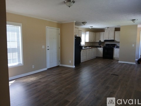 A kitchen with wooden floors and a black refrigerator.