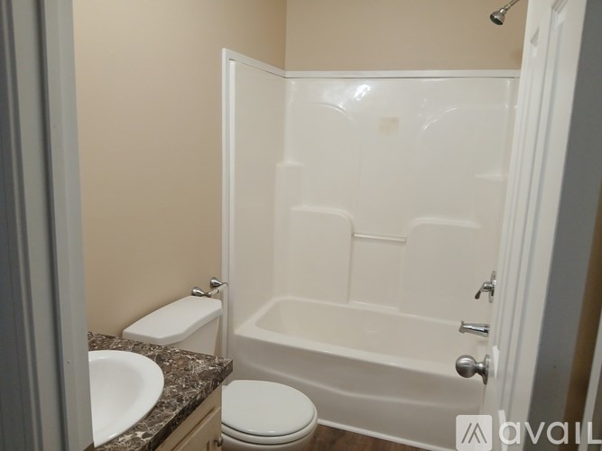 A white toilet sits next to a white bathtub in a bathroom.