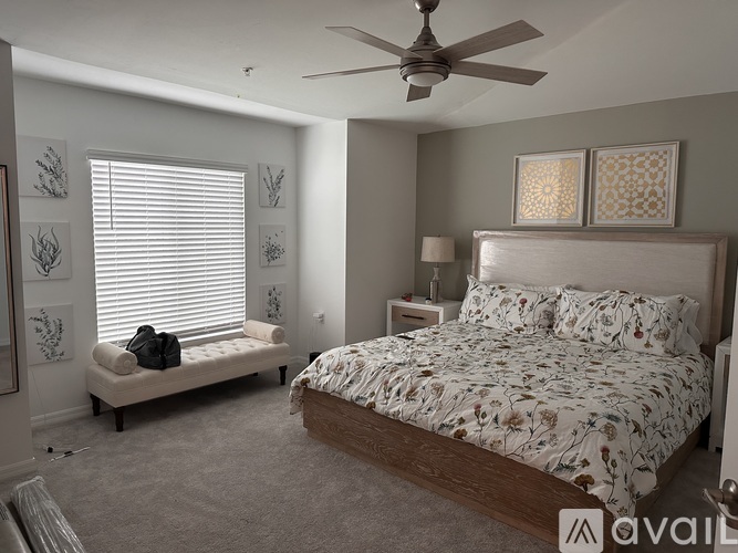 A bedroom with a large bed and a bench by the window.