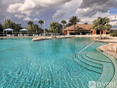 A large swimming pool with a curved edge and a white fence around it.