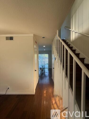 A long hallway with a staircase on the right and a door at the end.