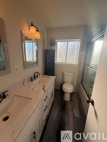 A bathroom with a toilet, sink, and mirror.