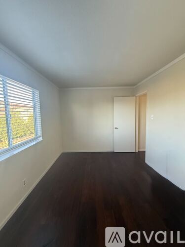 A room with wooden floors and a window with blinds.