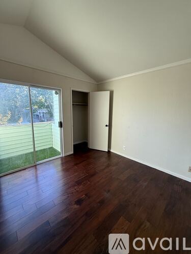 A room with wooden floors and a sliding glass door leading to a backyard.