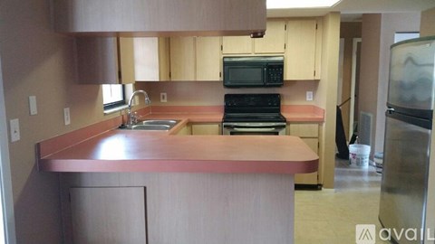 A kitchen with a stove, sink, and cabinets.