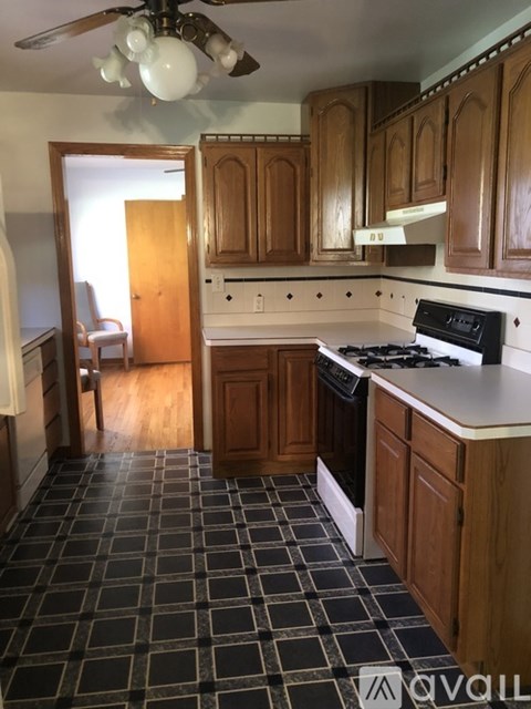 A kitchen with wooden cabinets and a black and white checkered floor.