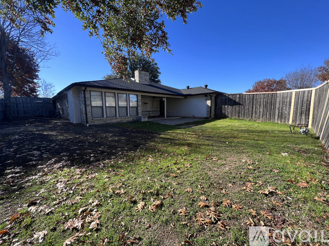 A house with a fence and trees in the background.