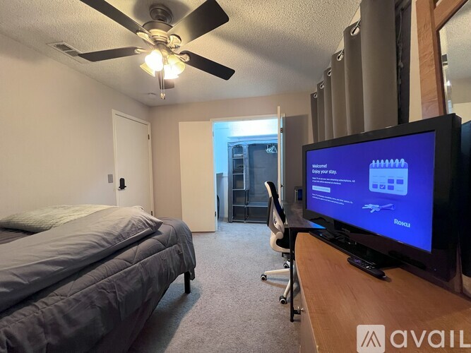 A bedroom with a bed, a television, and a ceiling fan.