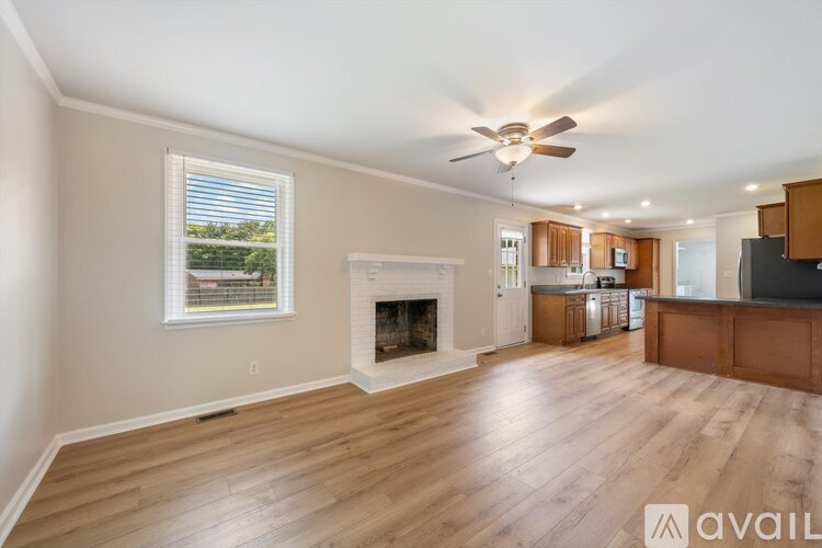 A spacious living room with a fireplace and a ceiling fan.