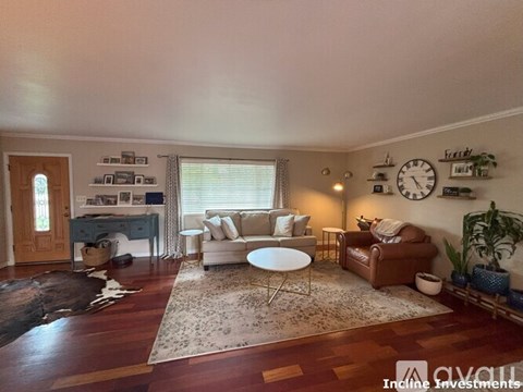 A living room with a brown couch, a white coffee table, and a rug on the floor.