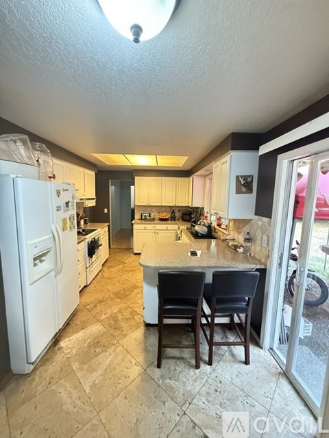 A kitchen with a white refrigerator and a marble countertop.