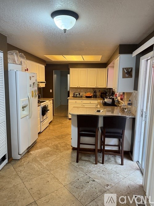 A kitchen with a white refrigerator and a tiled floor.