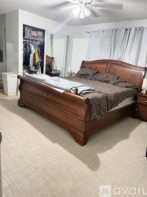 A bedroom with a large bed and a white ceiling fan.