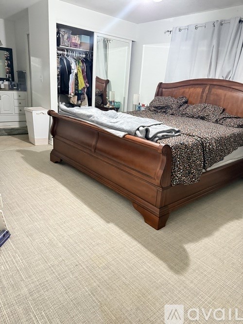 A bedroom with a bed, a wardrobe, and a trash bin.