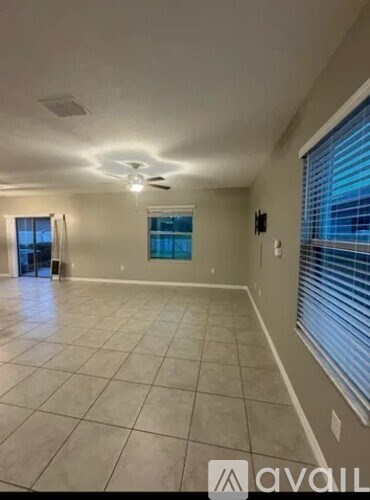 A spacious room with tiled flooring and a ceiling fan.