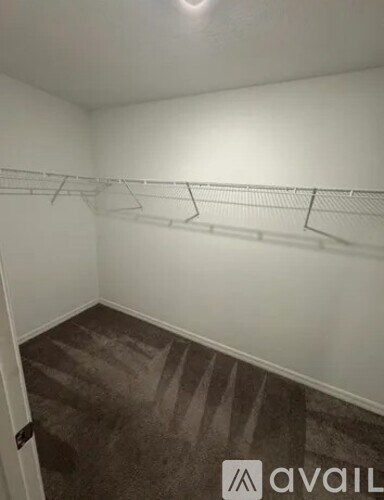 A room with a carpeted floor and a wall-mounted clothes rack.