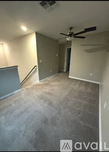 A room with a carpeted floor and a ceiling fan.