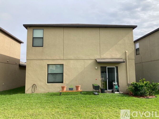 A beige house with a green lawn in front.