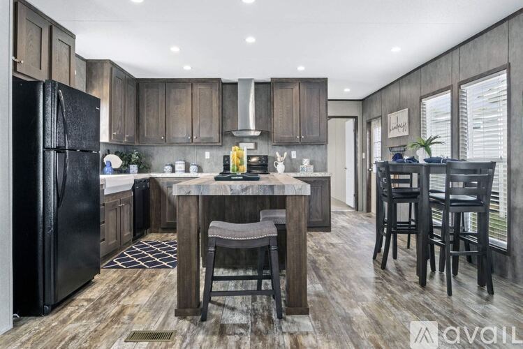 A kitchen with a black refrigerator and wooden floors.