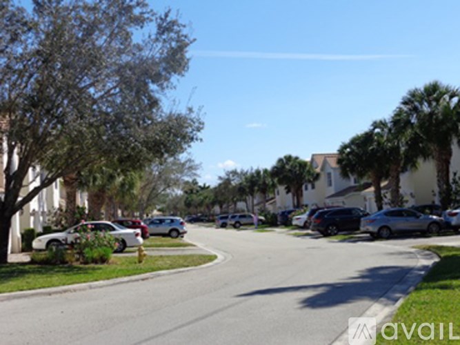 A street with cars parked on the side and trees lining the road.