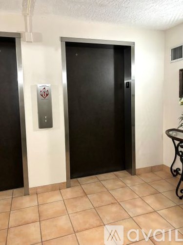 Two black elevators in a hallway with a logo on the left elevator.