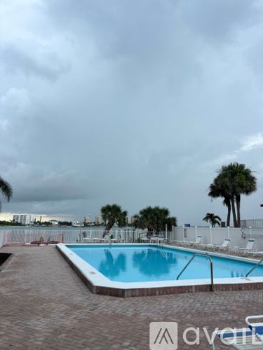 A pool surrounded by palm trees and a cloudy sky.