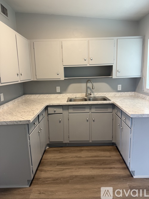 A kitchen with white cabinets and a marble countertop.