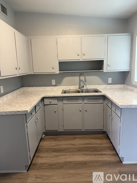 A kitchen with white cabinets and a marble countertop.