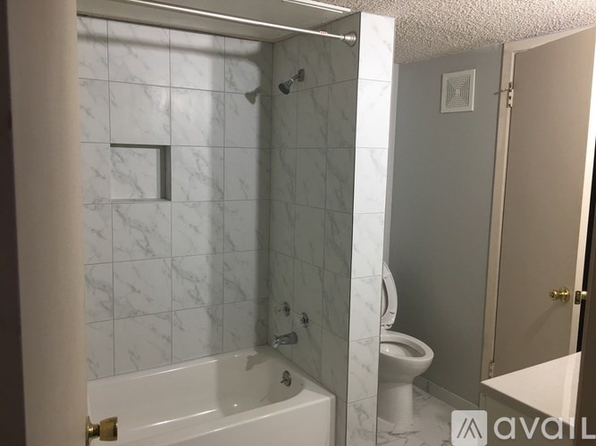 A bathroom with a marble tile wall and a white bathtub.