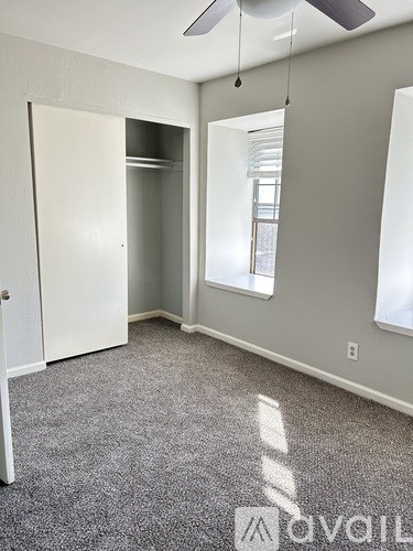 A room with a carpeted floor and a ceiling fan.