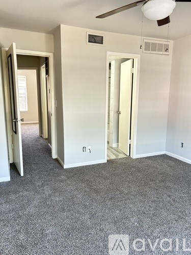 A room with a carpeted floor and a ceiling fan.