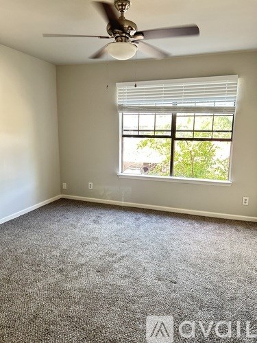 A room with a ceiling fan and a window with blinds.