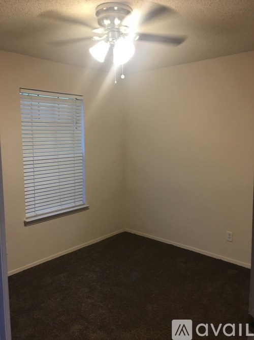 A room with a ceiling fan and a window with blinds.