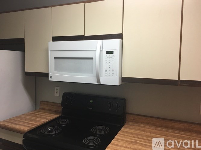 A white microwave oven is mounted above a black stove in a kitchen.
