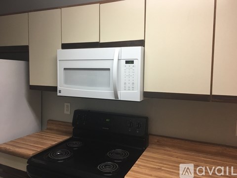 A white microwave oven is mounted above a black stove in a kitchen.