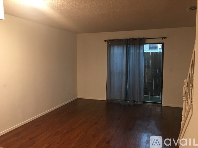 A room with wooden floors and a window with curtains.