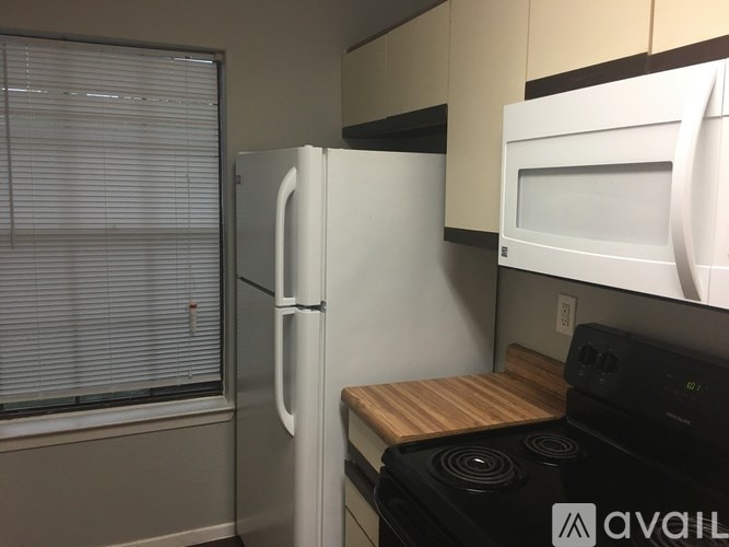 A kitchen with a white refrigerator, microwave, and black stove.