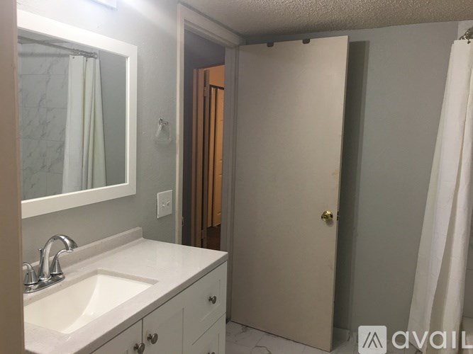 A bathroom with a sink, mirror, and shower curtain.