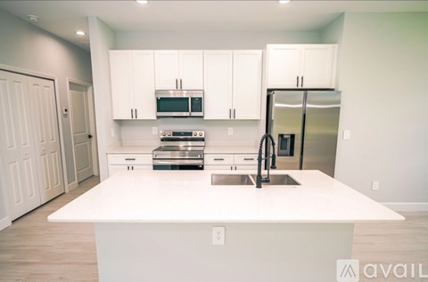 A kitchen with white cabinets and appliances is available for rent.