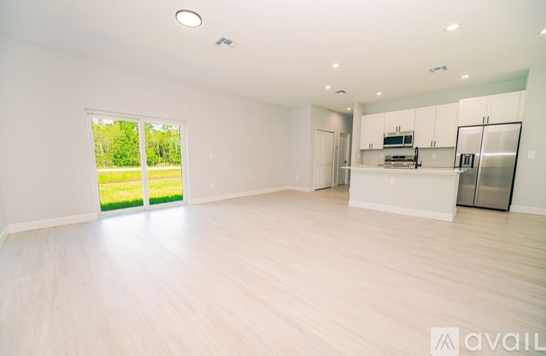 A spacious, empty room with white walls and wooden flooring.