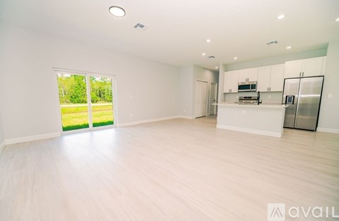 A spacious, empty room with white walls and wooden flooring.