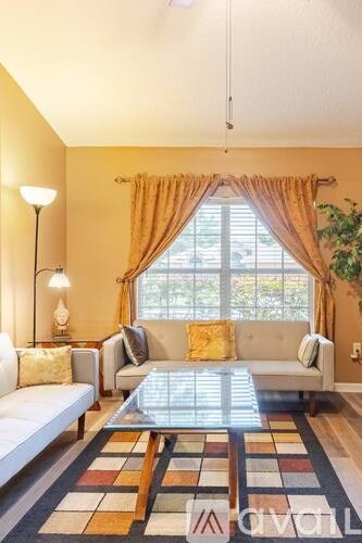 A living room with a white couch and a glass coffee table.