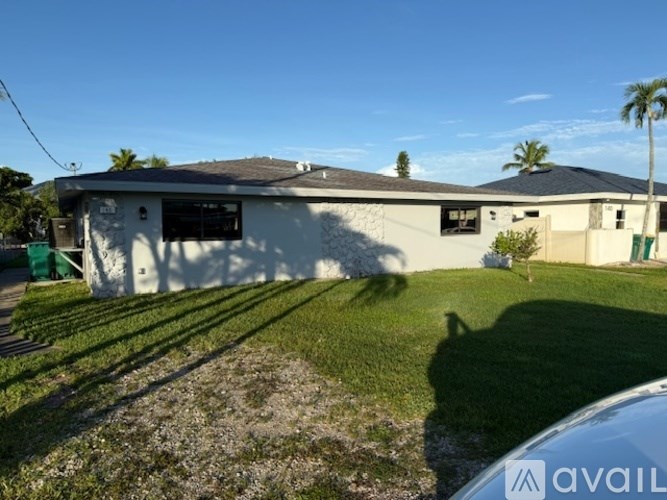 A white building with a green awning is in the foreground of a sunny day.
