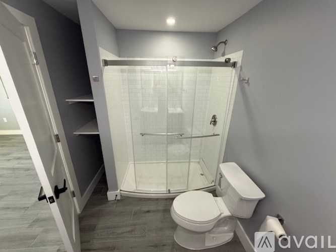 A white toilet is in a bathroom with a walk-in shower.