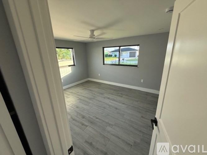 A room with a ceiling fan and two windows.